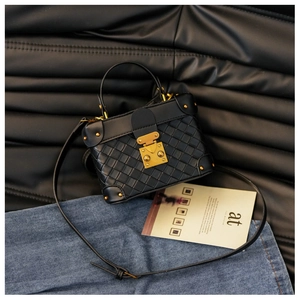 Close-up of black woven box bag with vintage gold lock and metallic rivets