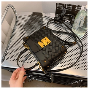 Detailed view of black woven bucket bag with golden metal lock and metal stand