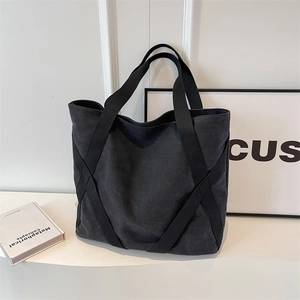 Large black canvas tote bag featuring reinforced cross straps and spacious design