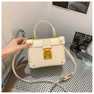 Close-up of white woven checkered bucket bag with vintage gold metal clasp and strap