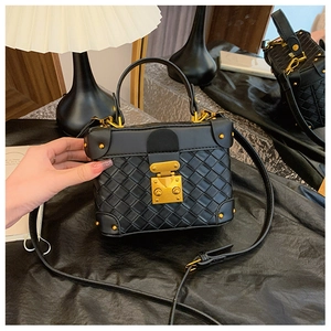 Detailed shot of black woven bucket bag with gold hardware and intricate textures