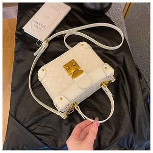 Detailed macro view of white woven texture square box bag with gold metal hardware lock