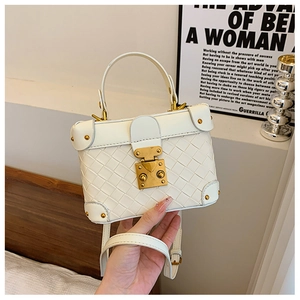 Detail of white woven mini bucket bag with gold hardware lock and adjustable strap