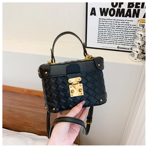 Close-up of a black woven leather bucket bag with gold rivets and metallic lock hardware