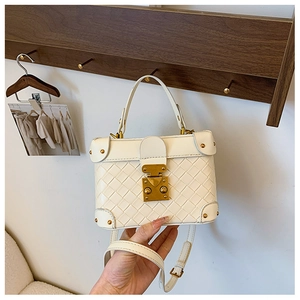Detail of cream woven leather bucket bag with gold clasp and reinforced rivet corners