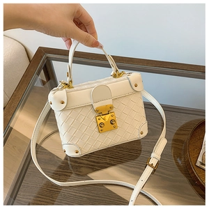 Detail of white woven leather box bag showing metallic hardware and reinforced corners