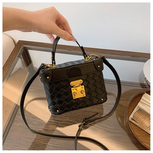 Detail of hand-held black woven bucket bag with vintage gold clasp and leather handle
