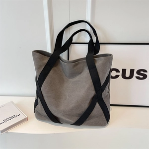 Minimalist grey canvas tote bag with black strap cross detail for daily commuting