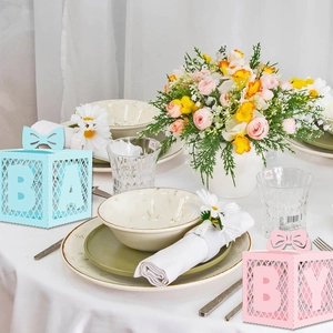 Pink and blue hollow baby shower favor boxes with ribbon on an elegant party table