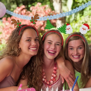 Trois femmes portant des serre-têtes de Noël festifs avec bois de renne et sapins à une fête
