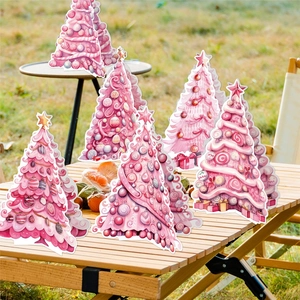 Décoration de table sapin de Noël rose avec ornements festifs sur table en bois