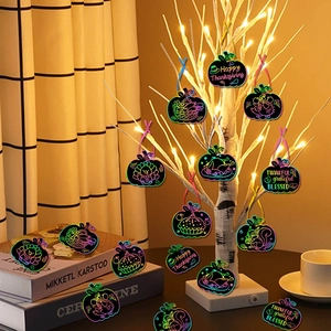 Thanksgiving pumpkin scratch art kit hanging on a warm lit decorative tree for home party