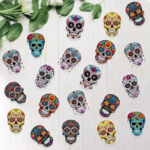 Sugar skull confetti stickers for Dia de los Muertos party decor on white wood background
