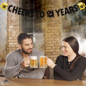 Cheers to 21 Years glitter banner with beer mugs for birthday party decor in bar setting