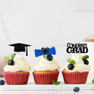 Glitter graduation cupcake toppers with black cap and blue scroll on marble surface