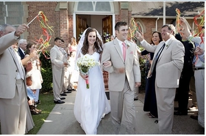Outdoor wedding scene with guests waving colorful ribbon wands for celebration