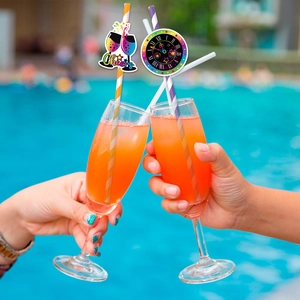 Close-up of Cheers and clock party straws for New Year celebration by the pool