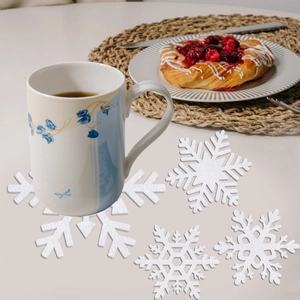 Set of four white snowflake coasters featuring intricate hollow design for festive table decor