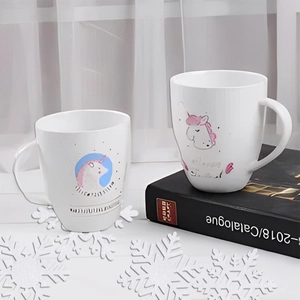 White ceramic unicorn mugs on books decorated with winter snowflake table ornaments