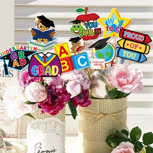 Kindergarten graduation party props with owl, diploma and star toppers in floral vase
