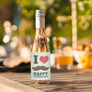 Outdoor shot of a Father's Day wine bottle sticker with happy greetings on a wooden table
