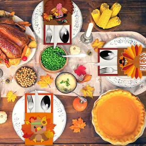 Three Thanksgiving turkey cutlery holders on a festive dinner table with pumpkin and roast turkey