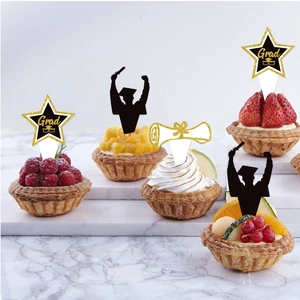 Graduation cupcake toppers with black silhouettes and gold stars on fruit tarts