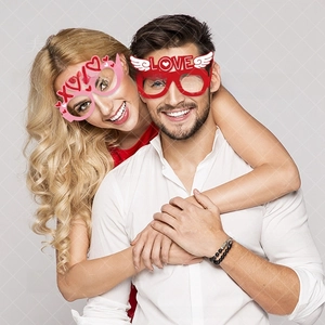 Close-up of couples wearing red Love and pink XOXO paper glasses for Valentine party