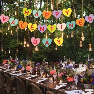 Colorful Happy Valentines Day heart banner hanging in a romantic outdoor forest dinner setting