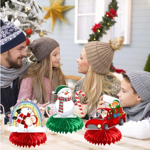 Three festive Santa and snowman honeycomb centerpieces displayed on a holiday dinner table