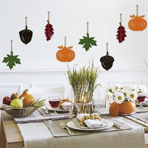 Detail of felt pumpkin and maple leaf hanging decorations on a festive fall themed wall