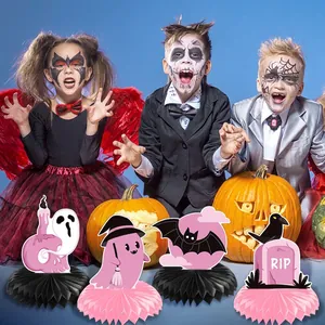 Pink and black Halloween honeycomb centerpieces featuring ghosts and bats on a party table