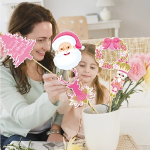 Close-up of pink Christmas photo props including Santa, nutcracker and tree on wooden sticks