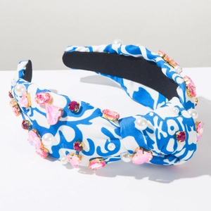 Close-up of tie-dye knotted headband with pink rhinestones and white pearls on fabric