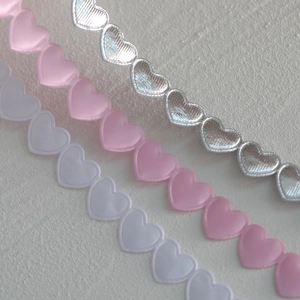 Macro detail of heart-shaped ribbon samples in white, pink, and metallic silver