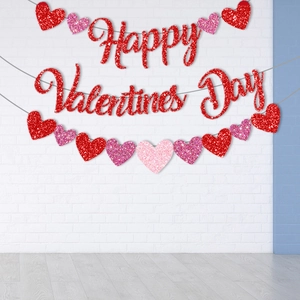 Glittery Happy Valentine's Day banner and heart garlands on a white brick wall