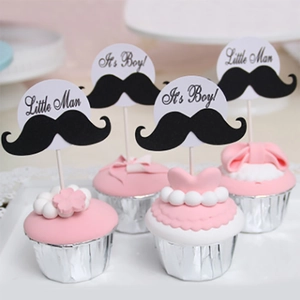 Detail of Little Man and It's a Boy mustache cupcake toppers on pink cream desserts