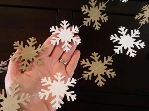 Close-up of white and gold paper snowflakes hanging for winter holiday decoration