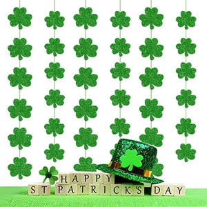 Green glitter shamrock garlands for St. Patrick's Day party decor hanging on white background