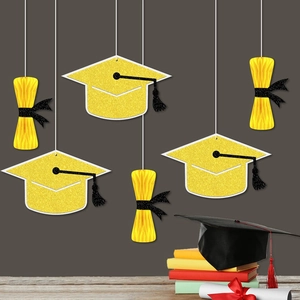Hanging graduation party decorations with honeycomb balls, gold glitter caps, and tassels