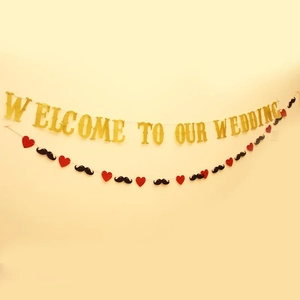 Close-up of golden glitter Welcome to Our Wedding banner with red heart and mustache deco