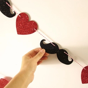 Detail of red glitter hearts and black mustache banner for party decorations