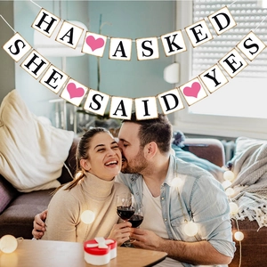 Detail of HE ASKED SHE SAID YES engagement banners hanging in a warm home party scene