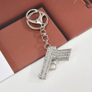 Macro detail of silver gun keychain with sparkling crystals and metal spring clasp