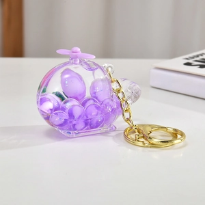 Purple helicopter keychain with floating bubbles and golden chain on a white surface