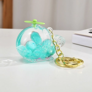 Detail of creative helicopter keychain with green glitter beads in liquid acrylic case