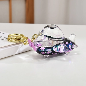 Detail of creative airplane keychain with blue moving sand liquid and pink cherry blossoms