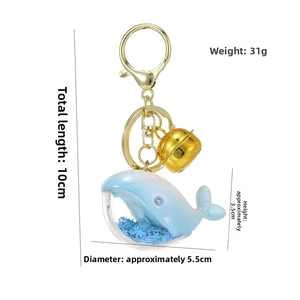 Detail view of a laser acrylic blue whale keychain with glitter and golden bell