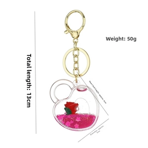 Macro detail of heart-shaped keychain with rose, pink liquid glitter and golden lobster clasp