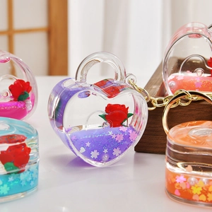 Close-up of heart-shaped acrylic liquid quicksand keychain with rose and star glitters